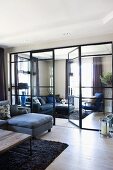 Seating in two large living rooms separated by glass partition wall and glass doors