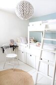 White, children's bedroom with black shelf and spherical paper lampshade with black polka dots; storage boxes integrated into bunk beds and country-house chair