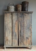 Old vessels on top of rustic cupboard against grey wall