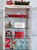 Open, glass-fronted cabinet with glasses & Christmas decorations