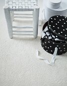 Shabby chic stool with woven seat and polka-dot hat box on white carpet
