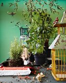 Tischplatte mit rostigem Vogelkäfig und Rosmarinpflanzen auf Blumenerde
