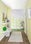 DIY renovations - hallway with floating shelves on yellow wall and pattern of green leaf stickers on grey wall