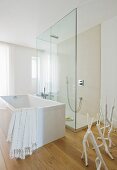 Light-flooded, designer bathroom with free-standing bathtub on parquet floor