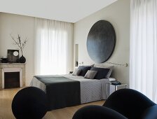 Elegantes Schlafzimmer mit französischem Bett, grauer Bettwäsche und rundem Kunstobjekt am Kopfende