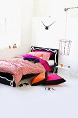 Bunte Bettwäsche mit Stofftier auf Holzbett mit verziertem Kopfteil und Drahtlampenschirm im Jugendzimmer