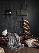 Furs draped over leather ottoman and ladders against embossed, anthracite wall