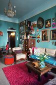 Many different framed pictures of women on turquoise wall in renovated, vintage-style period apartment
