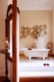 Screen with window next to doorway and view of free-standing, vintage bathtub in minimalist bathroom with Oriental motif on wall