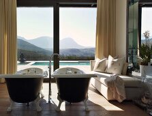 Luxuriöses Badezimmer mit zwei freistehenden, antiken Badewannen und einem prachtvollen Landschaftsblick