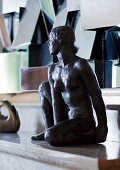 Statue of seated woman on mantelpiece; cubist sculpture with angled, reflective surfaces in background