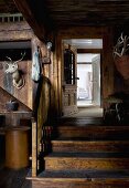 Former barn used as foyer - hunting trophies on wooden wall next to wooden steps leading to open door
