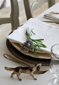 Dog ornament on table next to place setting with sprig of lavender on linen napkin