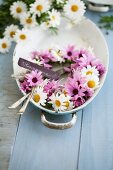 Wreath of pink and white daisies in baking dish with cutlery and name tag