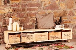 DIY sideboard with wine crates used as storage boxes against stone wall