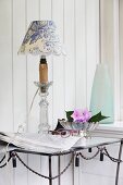 Table lamp with hand-crafted lampshade in white and blue toile de jouy fabric on metal table against wood-clad wall