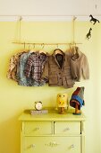 Improvised child's coat rack above chest of drawers