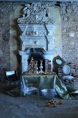 Ghost chair and Christmas arrangement on table in front of open fireplace with Greek-style, antique architectural elements in dilapidated ambiance