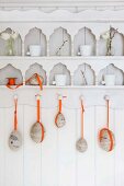 Ostereier mit orangefarbenen Bändern an verziertem Küchenregal aufgehängt