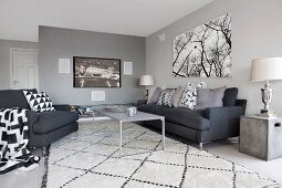 Charcoal sofa set with black and white scatter cushions and rug; flatscreen TV and picture of trees on walls