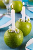 Green apples used as candlesticks decorated with chamomile flowers on dining table