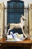Old rocking horse and patchwork blanket on antique table in front of wrought iron window grille