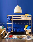 Blue children's bedroom for two - wooden bunk beds, wicker lampshade and wooden toys on woven rug