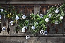 Rustic wooden balustrade of mountain hut balcony decorated with fir branches, crocheted stars and knitted baubles