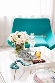 Kristall-Kerzenhalter auf Tabletttisch; im Hintergrund ein türkisfarbener Lounge Chair