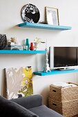 Flatscreen TV on pale blue floating shelf amongst other shelves and home accessories in living area