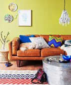 Dog sleeping on retro leather sofa with various scatter cushions against lime green wall, decorative wall plates, wooden floor and rug with geometric pattern