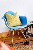 Graphically patterned pillow on light blue shell chair