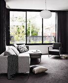 Wohnzimmer mit Sofagarnitur in puristischen Grautönen am Fensterfront