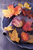 Herbstdekoration: Teller mit bunten, getrockneten und bemalten Herbstblättern
