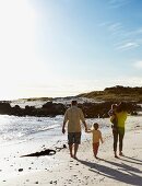 Familie mit zwei kleinen Kindern beim Spaziergang am Meeresstrand
