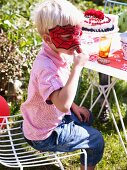 Junge mit Spiderman-Maske an Gartentisch