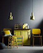 Yellow retro furniture against black wall; vintage-style half-height cabinet between chairs with yellow felt covers