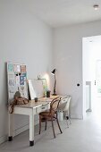 Nostalgic desk with desk lamp, two different chairs and pin board leaning against wall