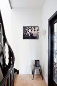 Klassiker Hocker aus Metall mit Behälter in Ecke eines Treppenhauses, an Wand gerahmtes, schwarzweiss Photo