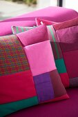 Patchwork scatter cushions in various shades of red and pink on deep pink couch