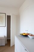 Fruit bowl on white sideboard and open interior door