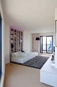 Wohnraum mit weißem Designersofa vor Einbauregal mit lilafarbener Umrahmung und grauem Teppich