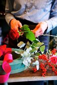 Frauenhände beim Schneiden einer Rose für einen Blumenkranz aus Steckschaum