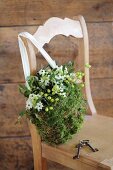 Romantischer Blütenbeutel aus Moos, Misteln und Milchsternen an Holzstuhl