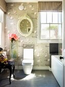 Eclectic bathroom with flamingo motif on wallpaper & nostalgic oval mirror on wall above modern toilet