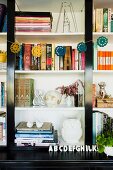 Bücherregal mit Girlande verziert und mit unterschiedlichen Vasen neben verschiedenen Büchern dekoriert