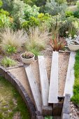 Rustic garden - steps edged with sleepers, white planters on steps, ornamental grasses and shrubs