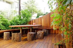Wooden terrace with DIY tree-trunk stools and table in urban garden