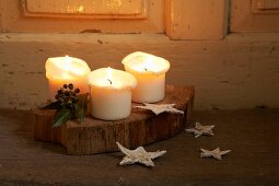 Brennende Kerzen mit Weihnachtsdeko auf Holzbrett und Boden
