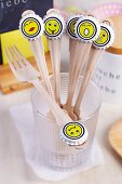 Wooden forks with whimsical smiley face stickers on bottle tops arranged decoratively for party buffet